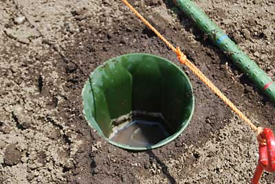 底を抜いた植木鉢を使って畝に穴を空けます。